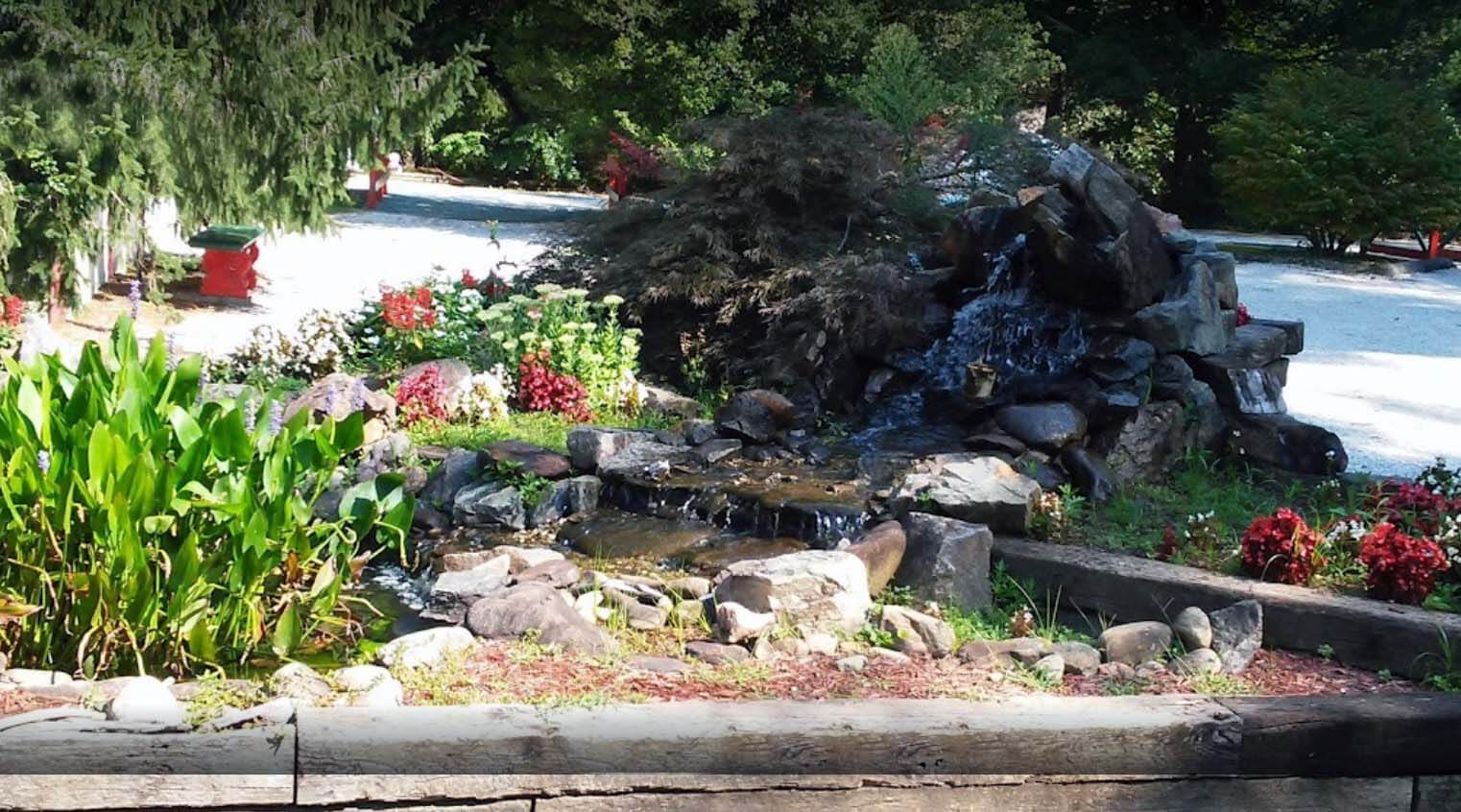 A serene garden pond surrounded by flowers and greenery.