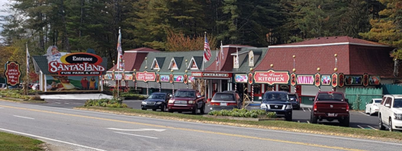 A roadside diner with classic cars parked outside in a wooded area.