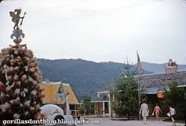 Town street with mountains in the background and a person walking.
