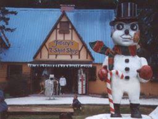 Large snowman statue outside a rustic hotel entrance with people nearby.