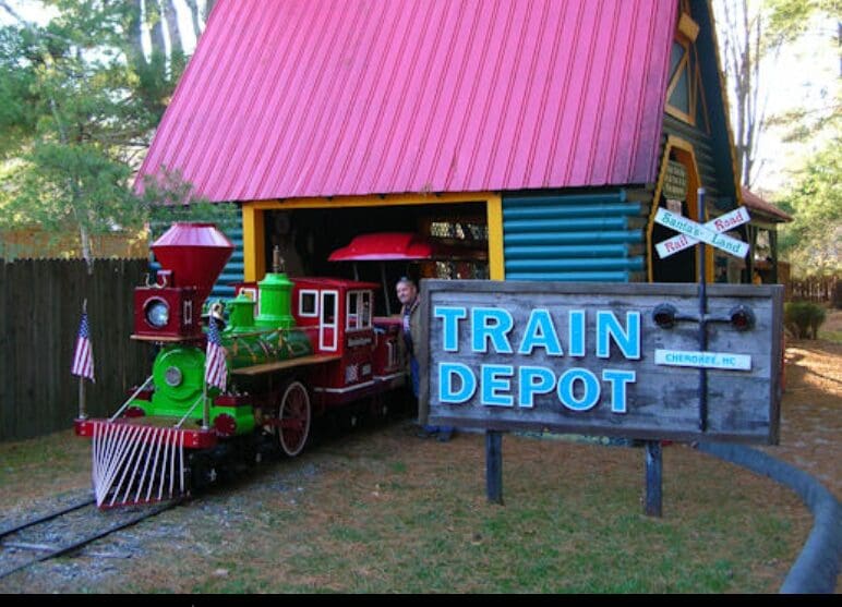 Colorful toy train outside a quaint train depot.